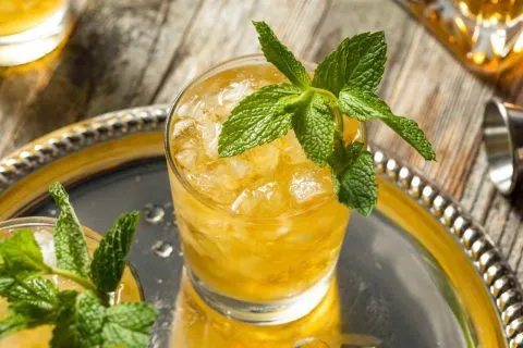 Glass of Honey Mint Julep cocktail garnished with fresh mint on a silver tray, perfect for summer sipping or Kentucky Derby celebrations.